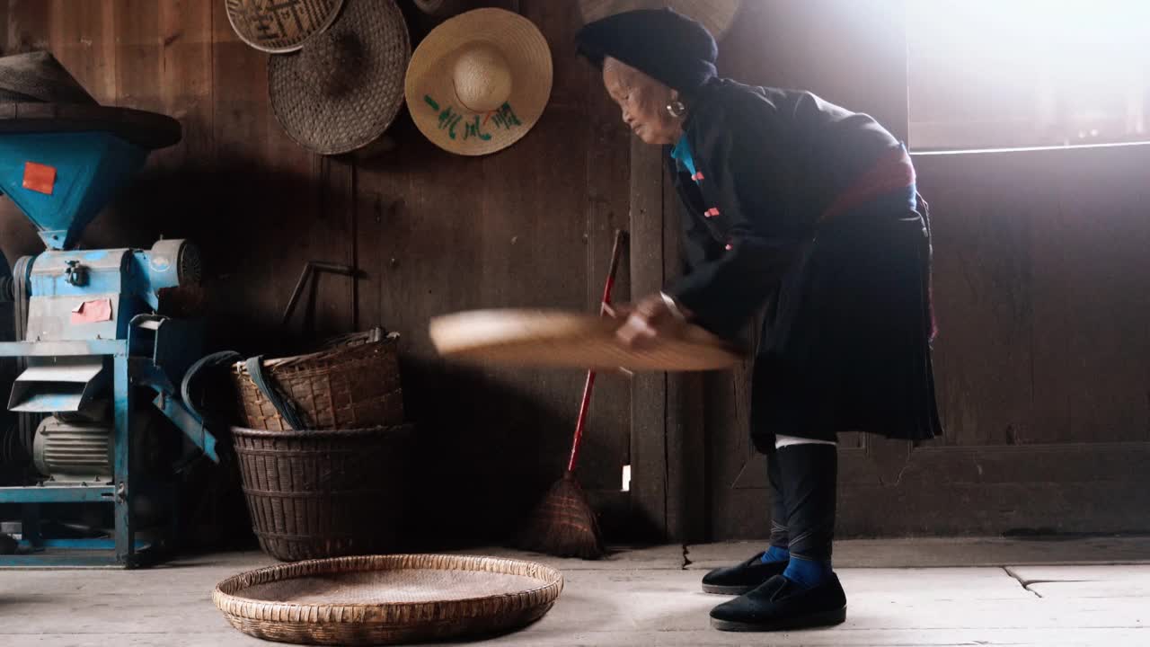 老少数民族中国妇女在农村的房子里筛大米视频下载