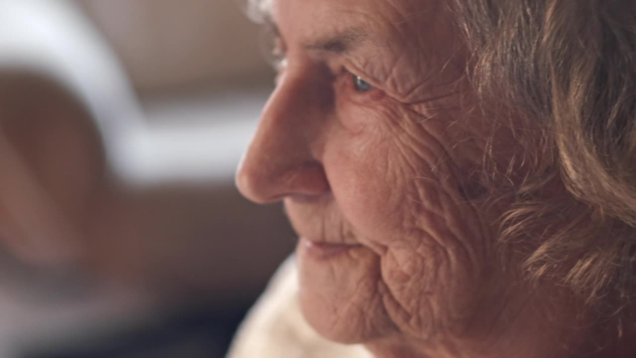 一个老妇人的特写脸，一个在家里的老妇人带着一个和病人谈话的医生。视频下载