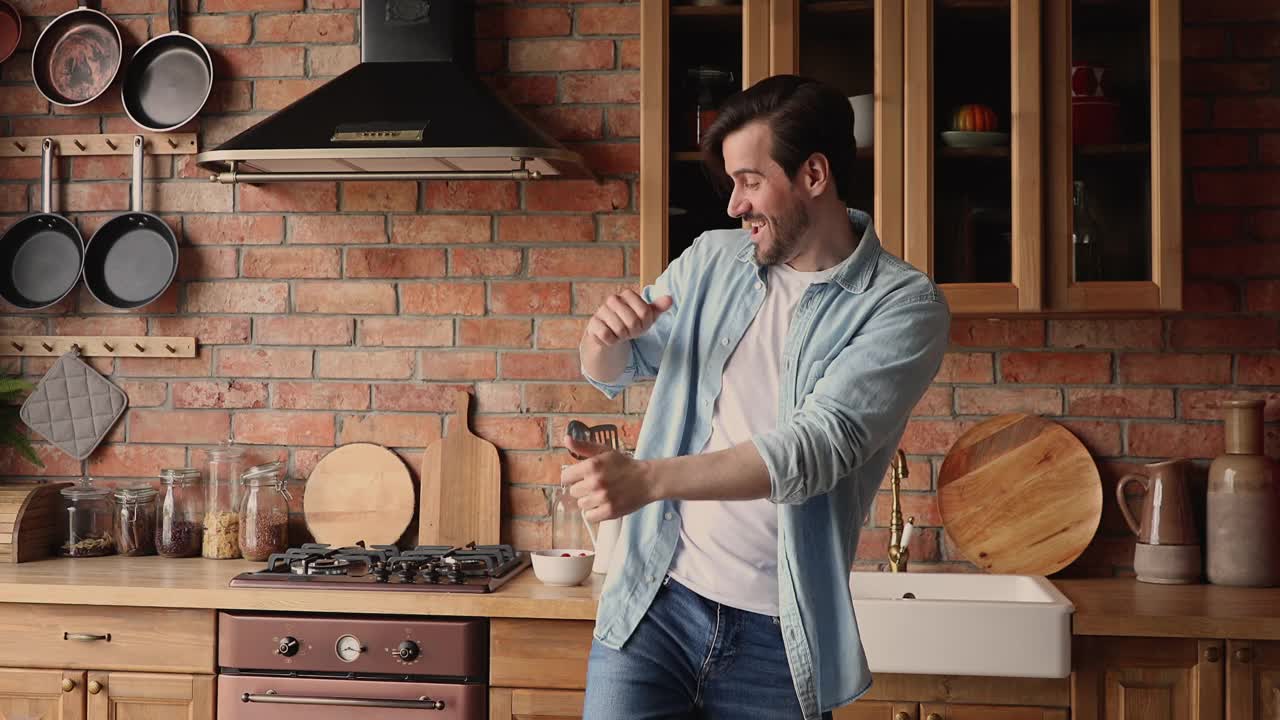 单身男子在现代厨房里翩翩起舞，无忧无虑享受周末视频素材