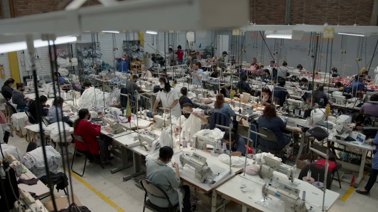 一群在服装厂工作的拉丁美洲员工，每个人都在自己的工作岗位上戴着防护口罩视频下载