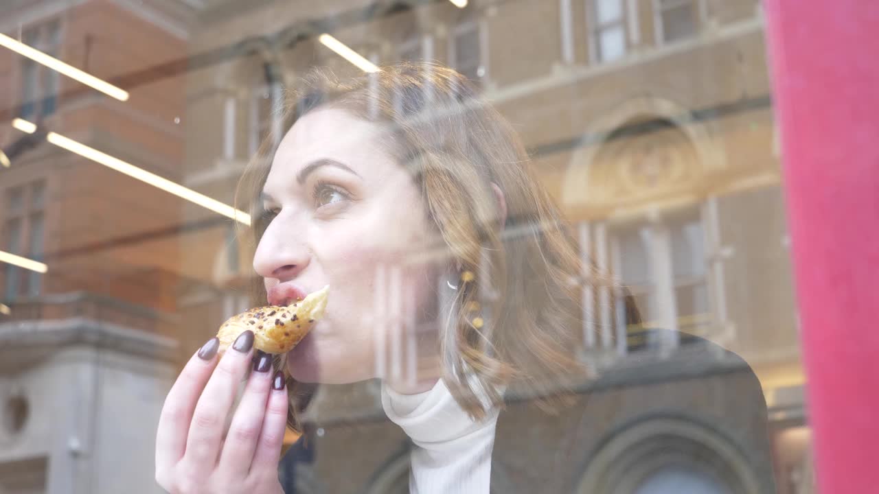 一个年轻女子在咖啡馆吃牛角面包的慢镜头视频下载