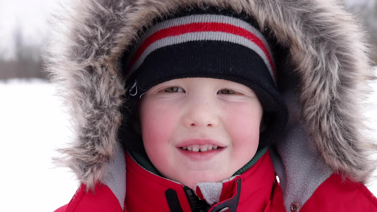 小男孩肖像在户外玩在冬天暴风雪和看相机视频下载
