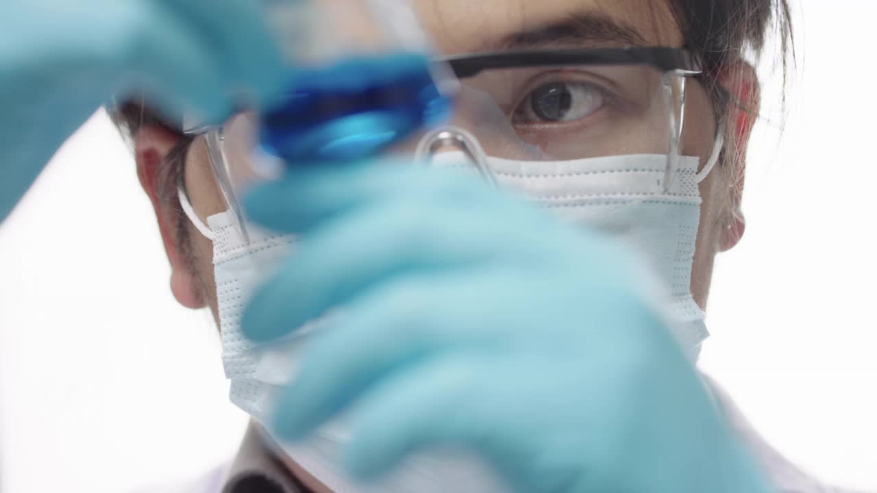 亚洲人在实验室玻璃器皿中混合蓝色化学物质视频下载