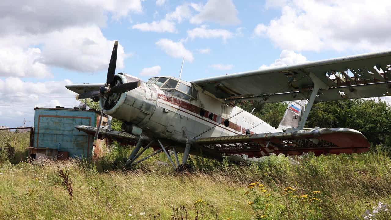 被毁坏和遗弃的旧飞机站在杂草丛生的田野里视频下载