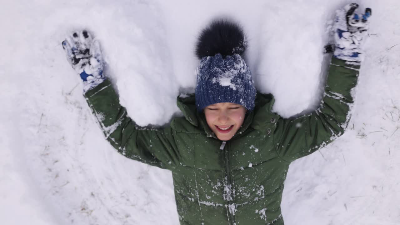 十几岁的男孩喜欢在新雪中做一个雪天使视频下载