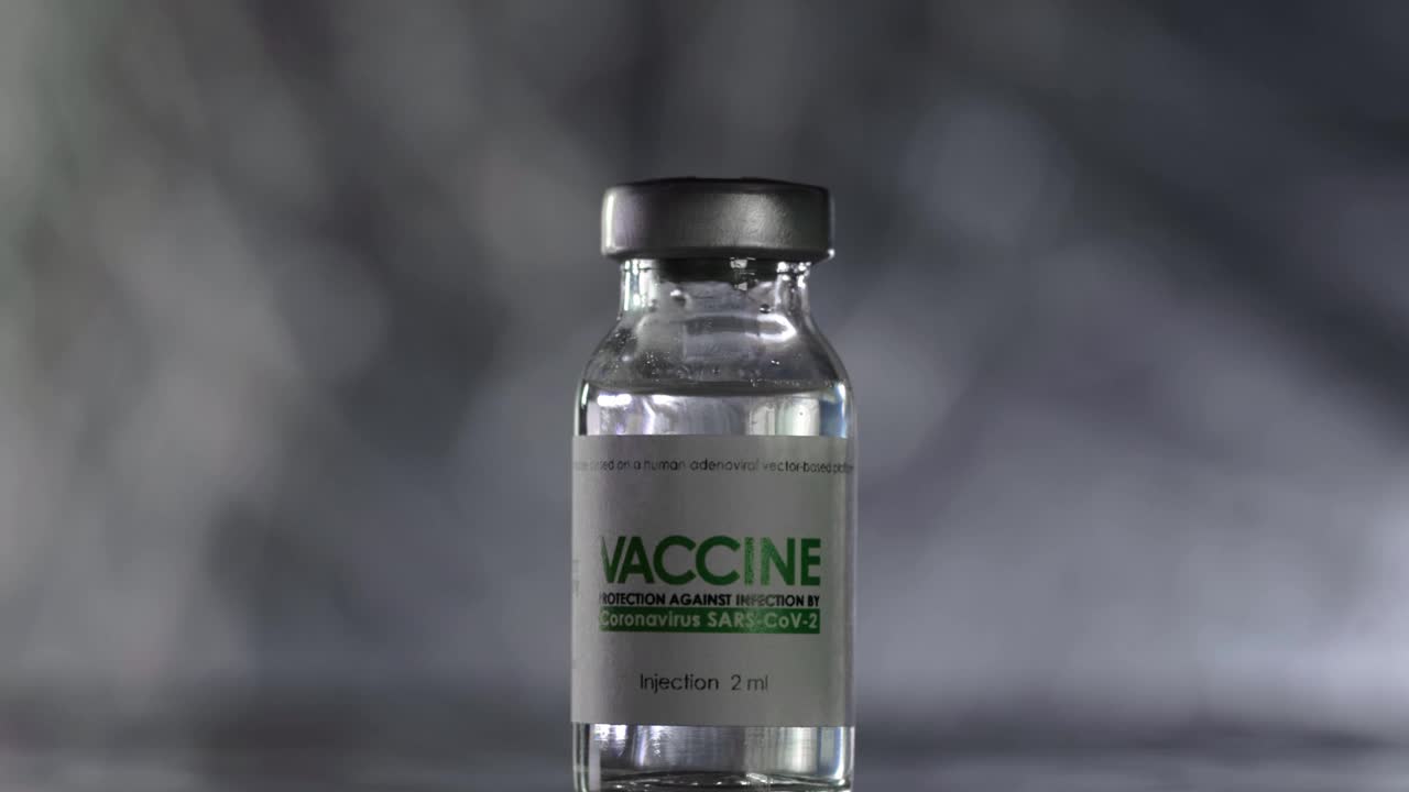 医生在注射前将治疗COVID-19冠状病毒的疫苗瓶子装满注射器。接种疫苗的概念,大流行。针穿过瓶盖，进入小瓶内。宏观的手在医疗手套视频素材