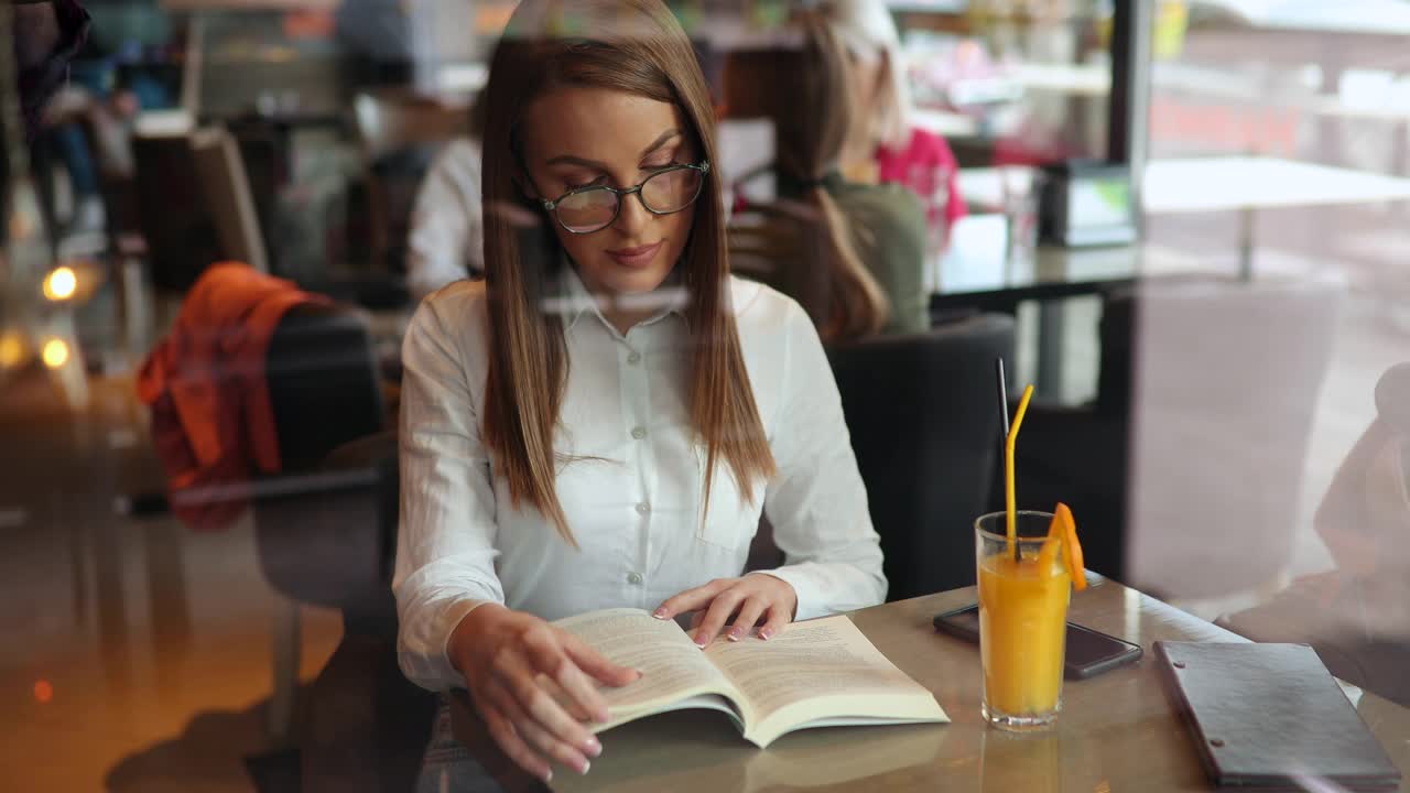 年轻女子在咖啡店看书视频下载