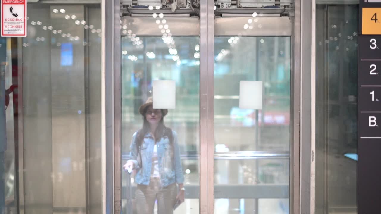 在机场，一名女士带着行李从电梯里走出来。视频下载