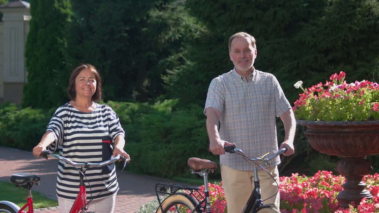 快乐的老年夫妇站在自然背景的自行车。视频素材