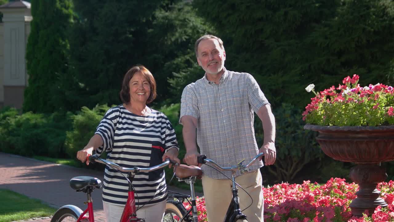 快乐的老年夫妇与自行车在夏季公园。视频素材