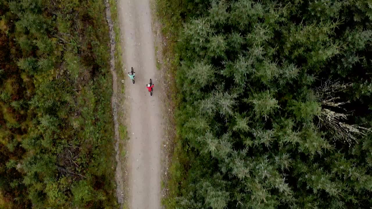 头顶上的无人机视图，两个山地自行车沿着森林自行车道骑行视频素材