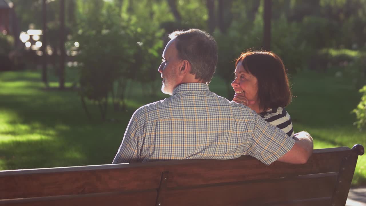 一对快乐的老夫妇坐在公园的长椅上。视频素材