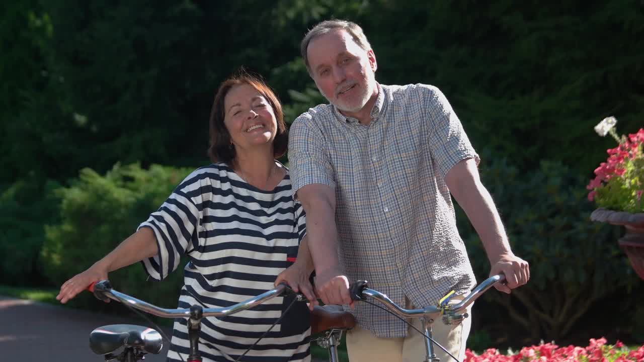 快乐的老夫妇与自行车有乐趣在城市公园。视频素材