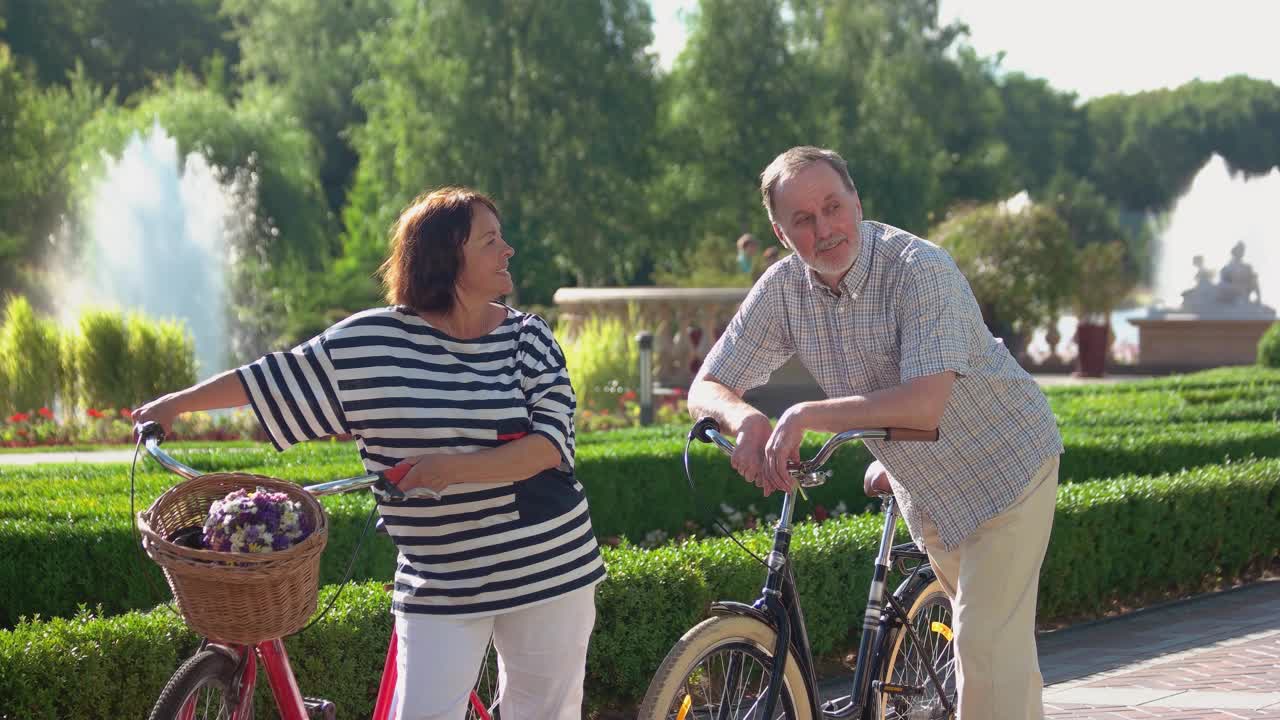 欢乐的老年夫妇骑着自行车在夏季公园。视频素材
