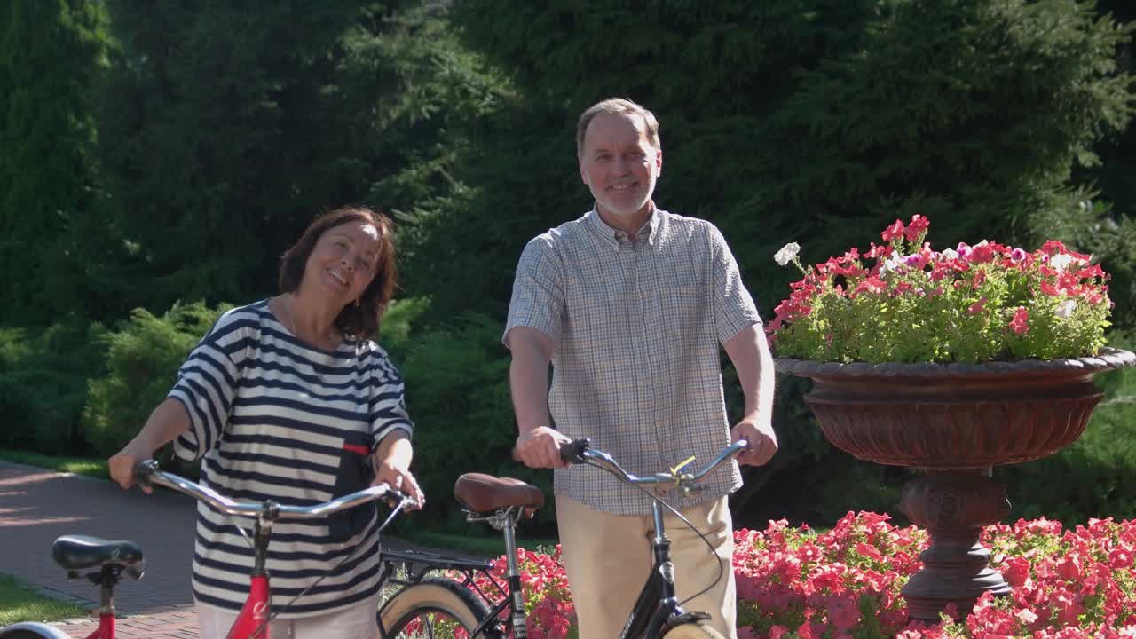 一对兴高采烈的老夫妇在公园里骑着自行车。视频素材
