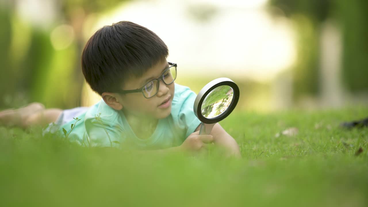 孩子用放大镜在户外学习。概念、自我学习和环境视频下载
