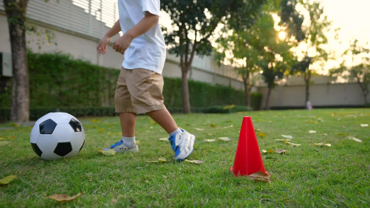 亚洲小孩在公园里踢足球，在房子的后院。假期和健康的概念视频素材