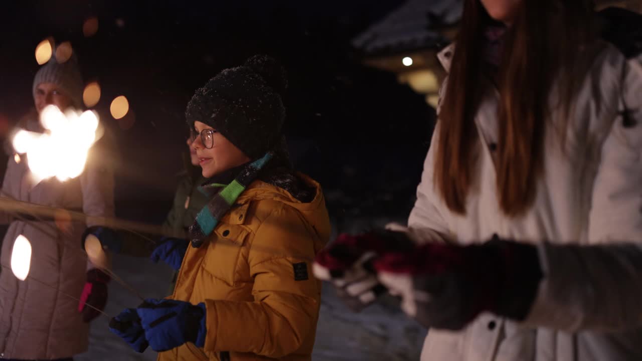母亲和孩子们在冬天的晚上享受火花视频素材