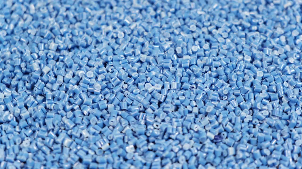二次颗粒由聚丙烯制成，蓝色塑料颗粒破碎到桌子上。工业用塑料颗粒原料。聚合物树脂。原塑料回收概念。视频下载