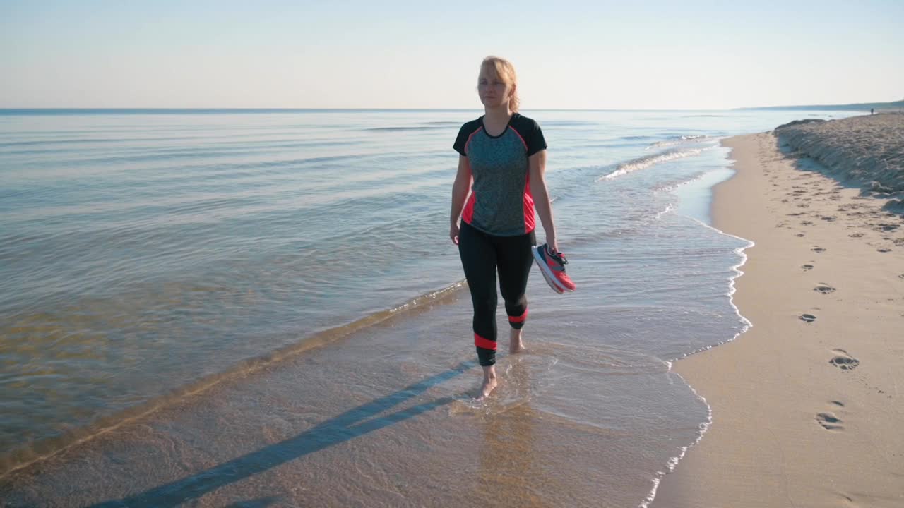 在海滩上赤脚行走的女人视频素材