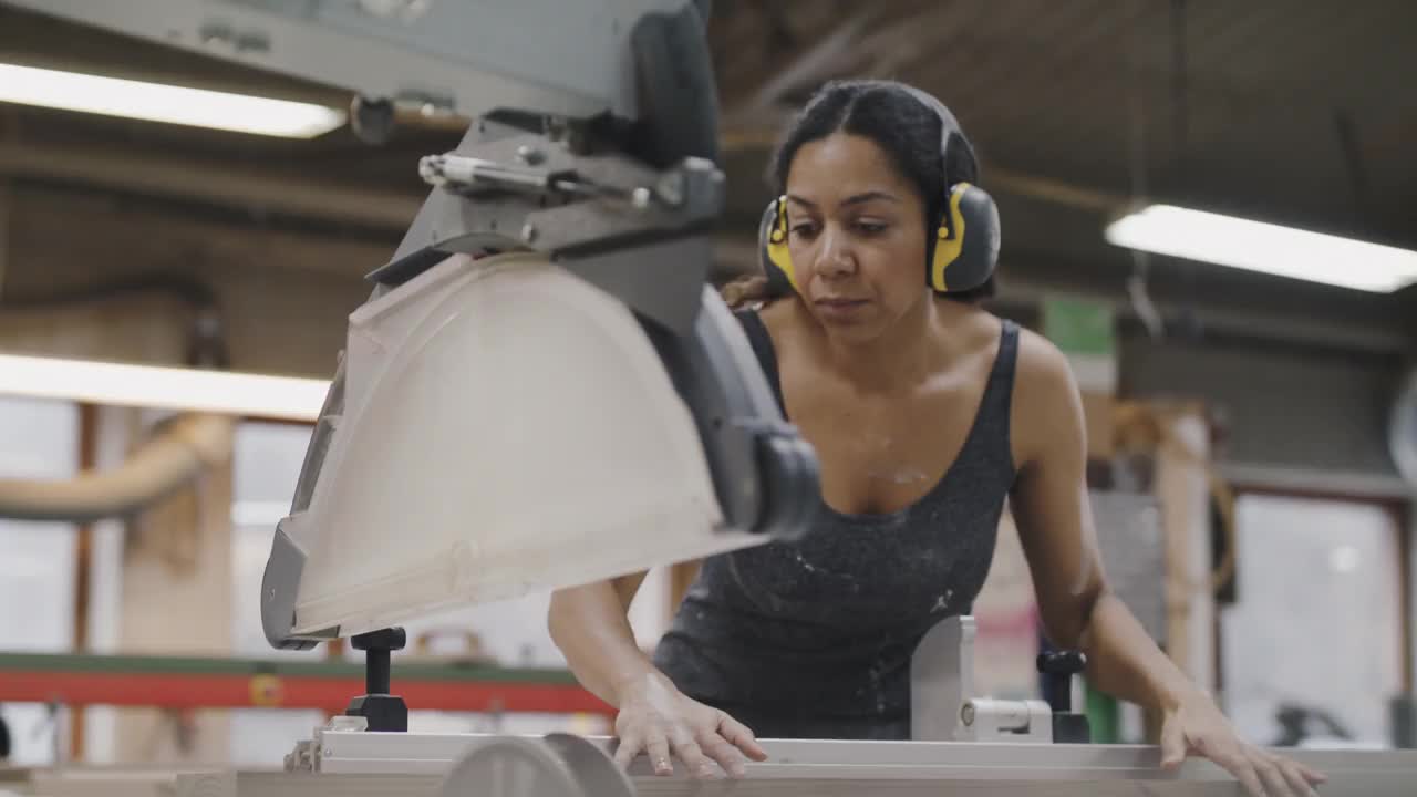 手持式拍摄的工匠切割木板在桌子锯在照明车间视频下载