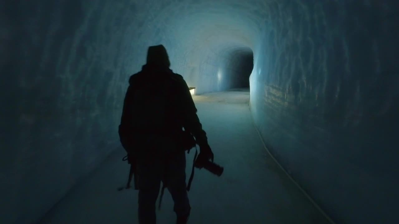 在欧洲冰岛的冰洞里，一名摄影师背着相机和背包。视频素材