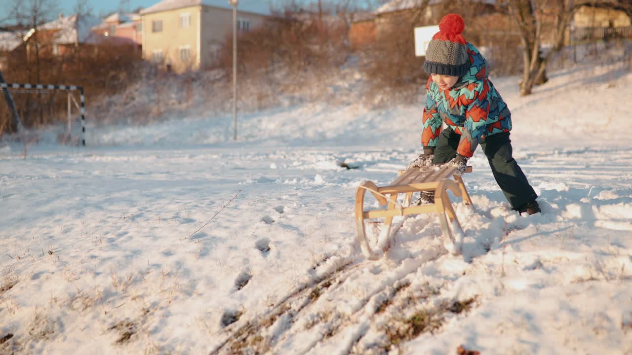 可爱的小男孩坐在雪橇上视频下载