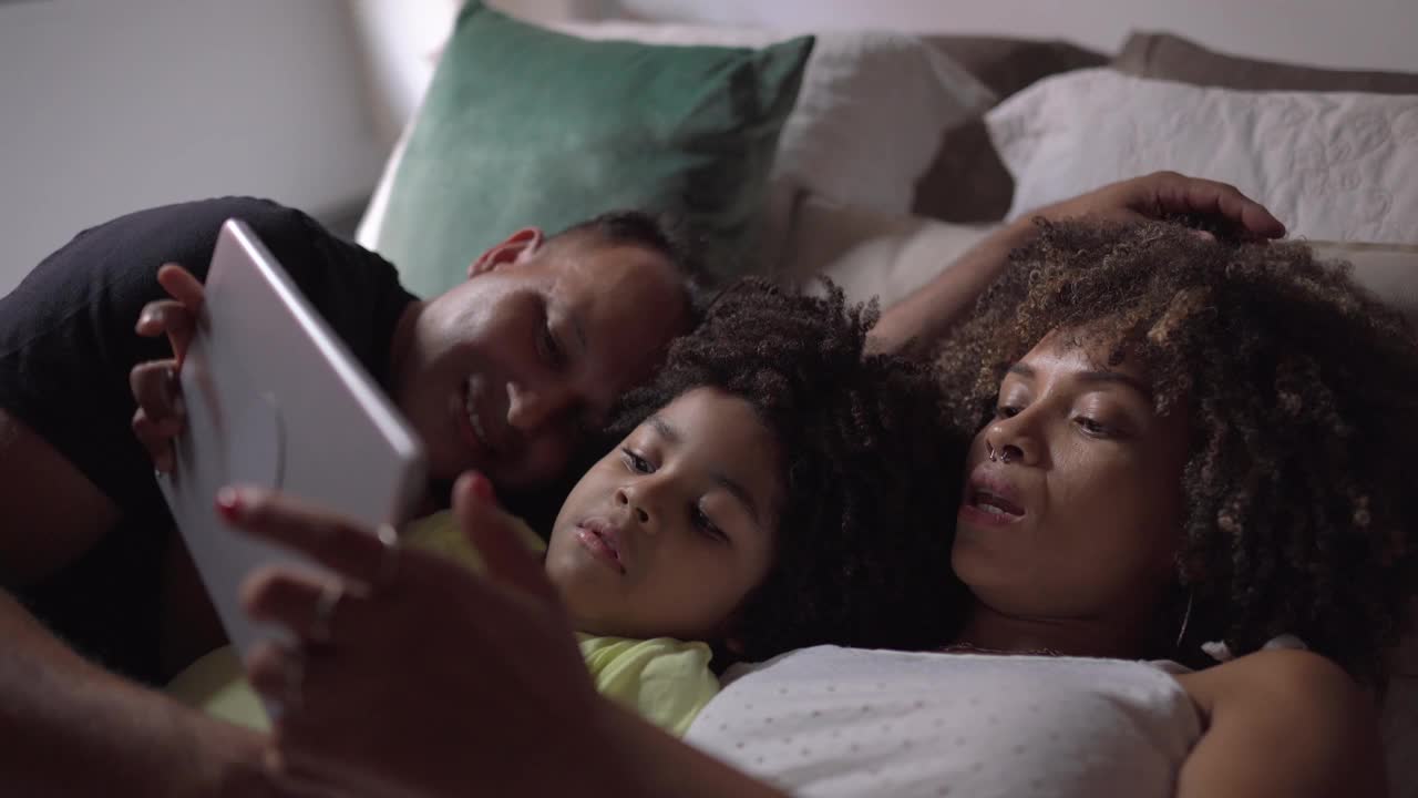 家人躺在床上用平板电脑看视频或电影视频素材