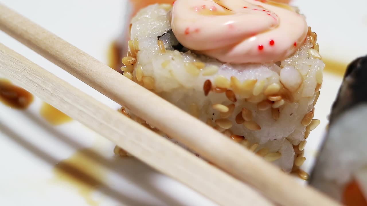 分子烹饪。混合了日本食品和美国快餐。日本寿司和卷的特写镜头。在白色盘子中平稳旋转。酱和棍棒。视频素材
