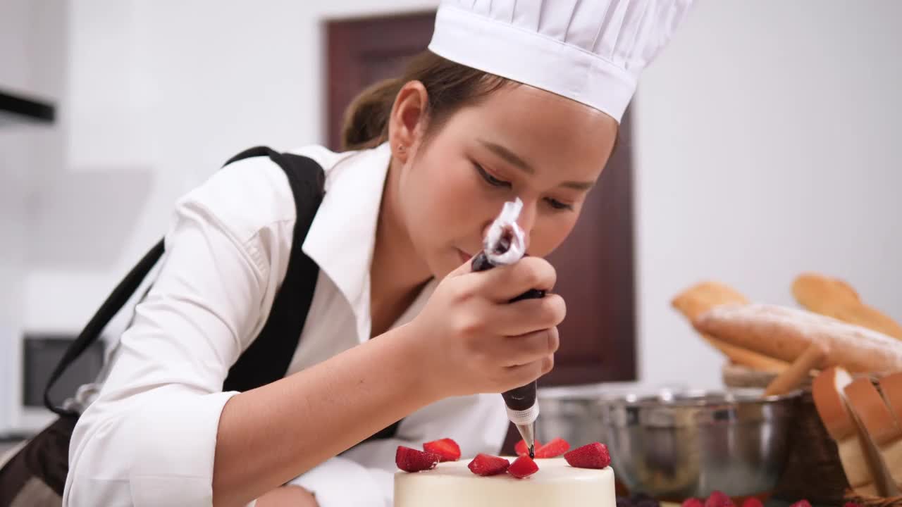 年轻的亚洲夫妇在厨房里愉快地做蛋糕和面包。视频下载