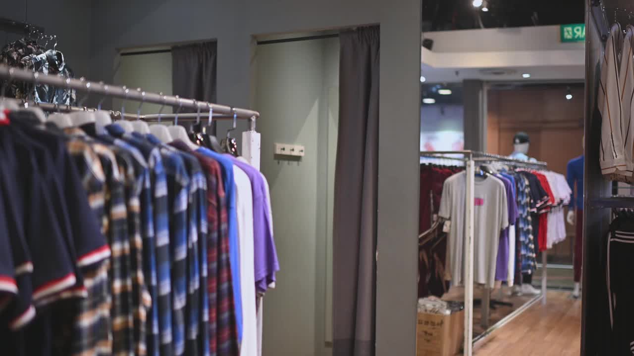 亚洲华人男性手拿男装衬衫在服装店尝试选择正确的一件购物视频下载