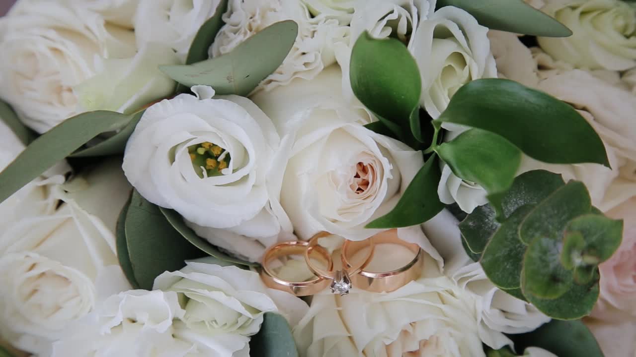 婚戒和订婚戒指的特写镜头躺在婚礼花束上视频素材