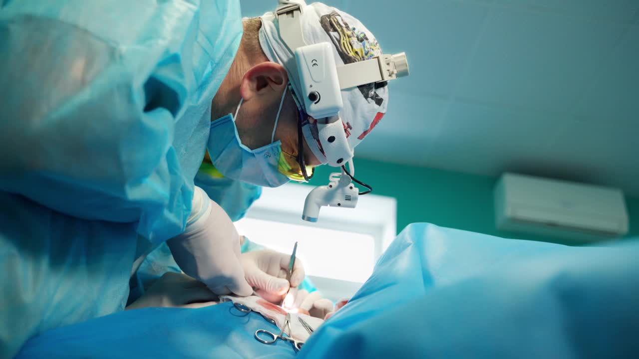 外科医生头部手电筒的侧面图。外科医生在手术室用医疗工具给病人做手术。特写镜头。视频下载