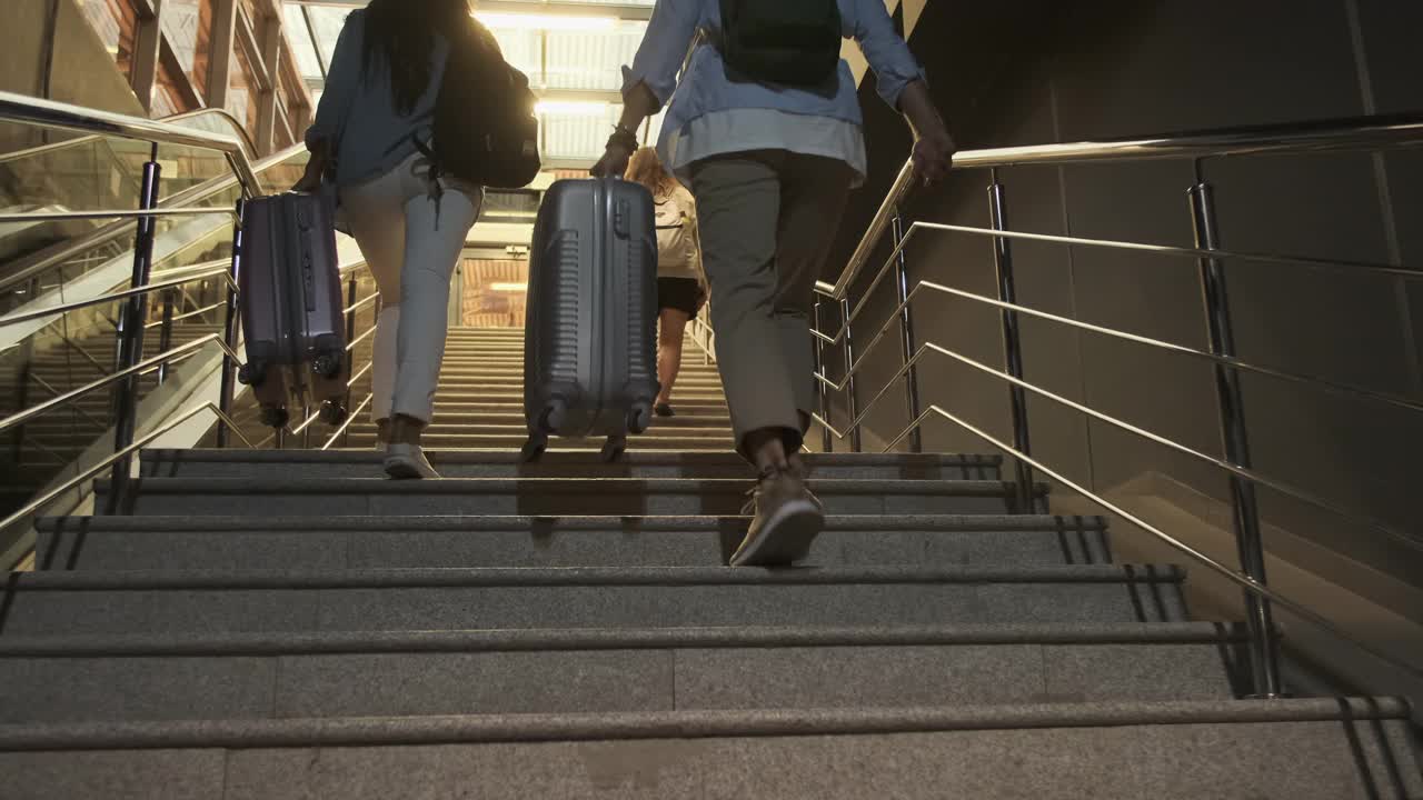 年轻的朋友们手拿行李箱爬上台阶视频素材