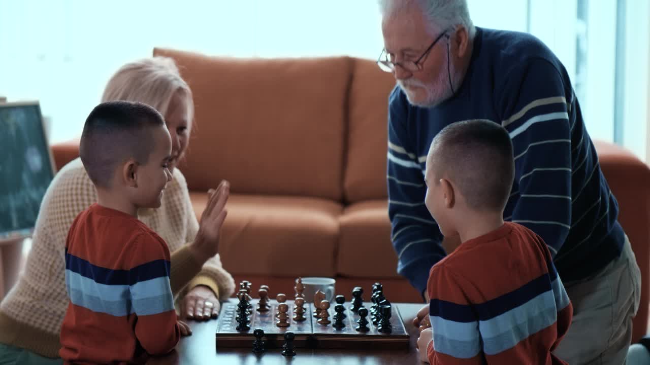 下棋结束后，大胡子的爷爷给他的小孙子和奶奶击掌。视频素材