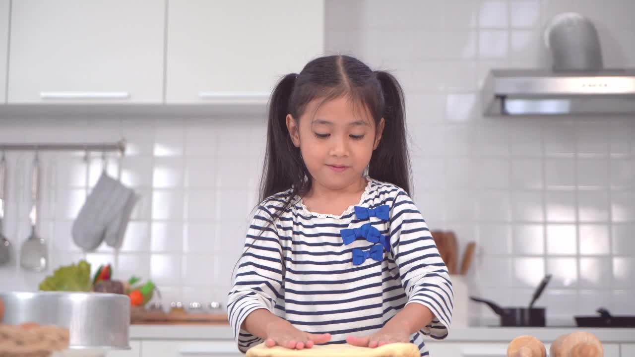 亚洲小女孩正在为面包店厨房揉面和准备面团。视频素材