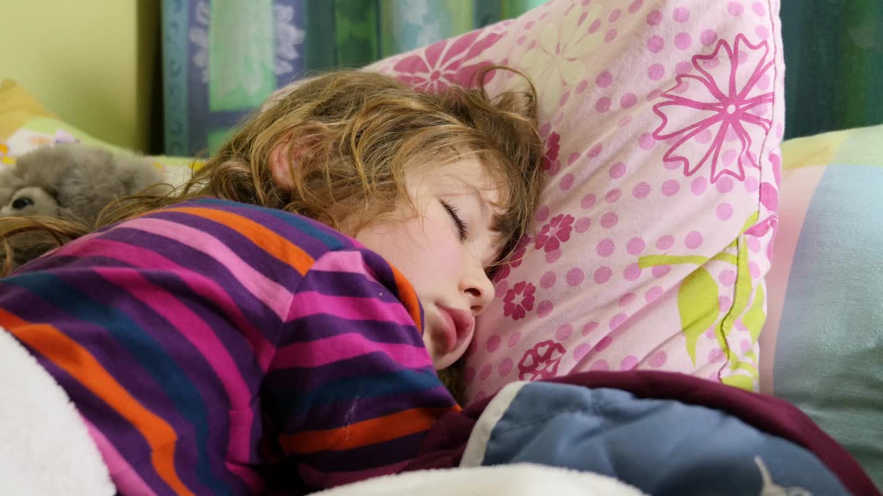 可爱的小女孩和她的软玩具一起睡觉视频素材