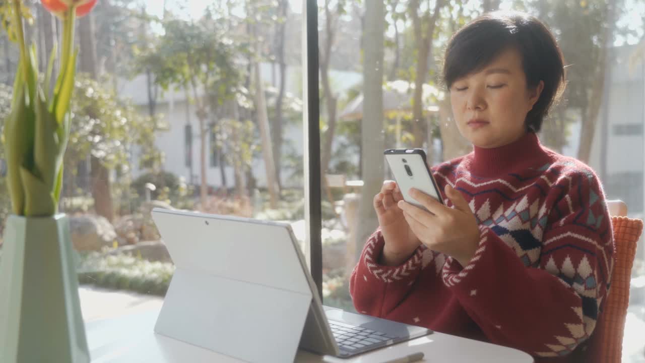 亚洲女性在家里使用笔记本电脑和智能手机视频素材