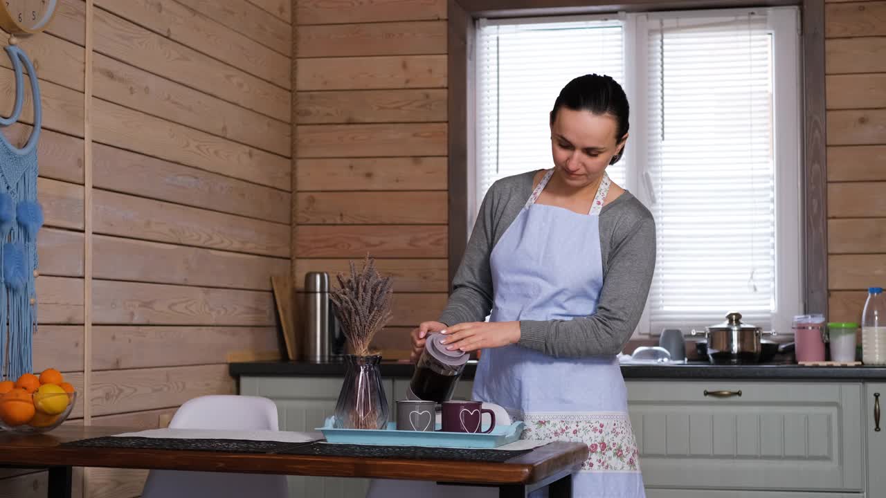 在厨房里往杯子里倒热茶的女人视频下载