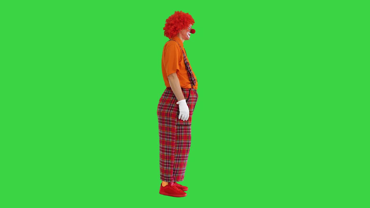 有趣的小丑站在红色裤子和某人在绿色屏幕上交谈，Chroma Key视频素材