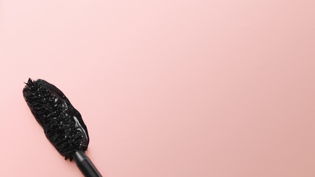 近距离和慢动作的黑色睫毛膏创造了一根睫毛棒在浅粉色的背景视频下载