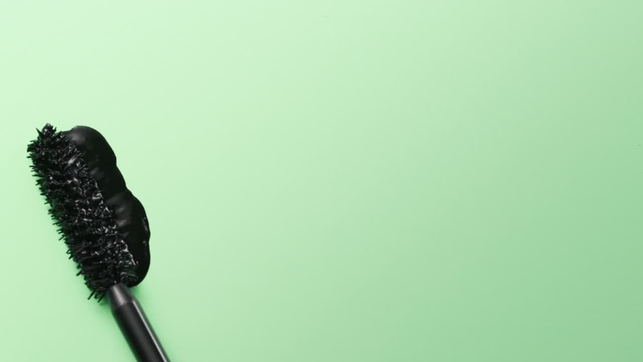 近距离和慢动作的黑色睫毛膏创建的睫毛膏棒在绿色的背景视频素材