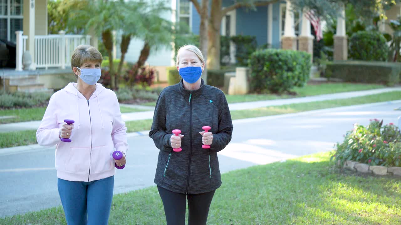 两名老年妇女戴着护手和口罩走路视频下载