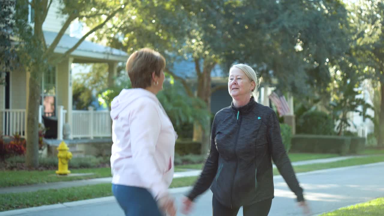 两个老年妇女在院子里跳爆竹，拥抱着视频素材