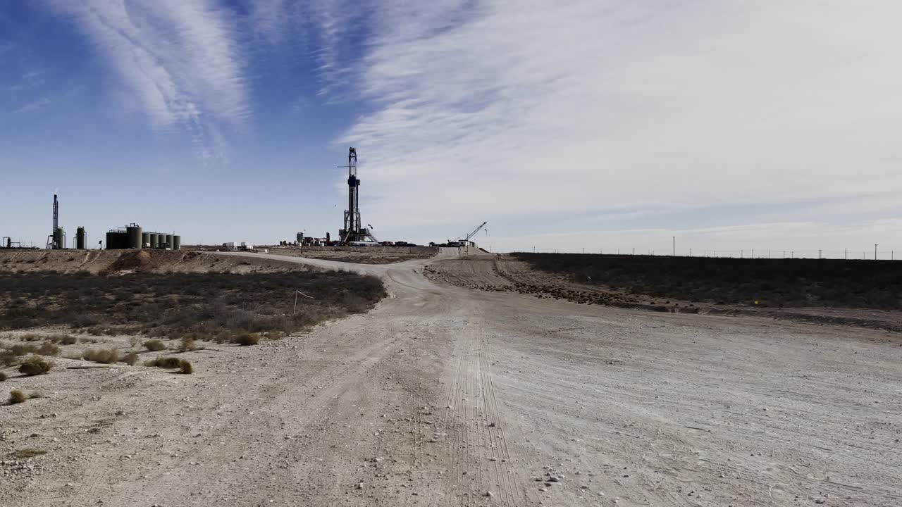 在德克萨斯州西部，两名年轻的油田工人穿着防护装备、防火工作服和安全帽走向水力压裂石油和天然气钻井平台视频素材