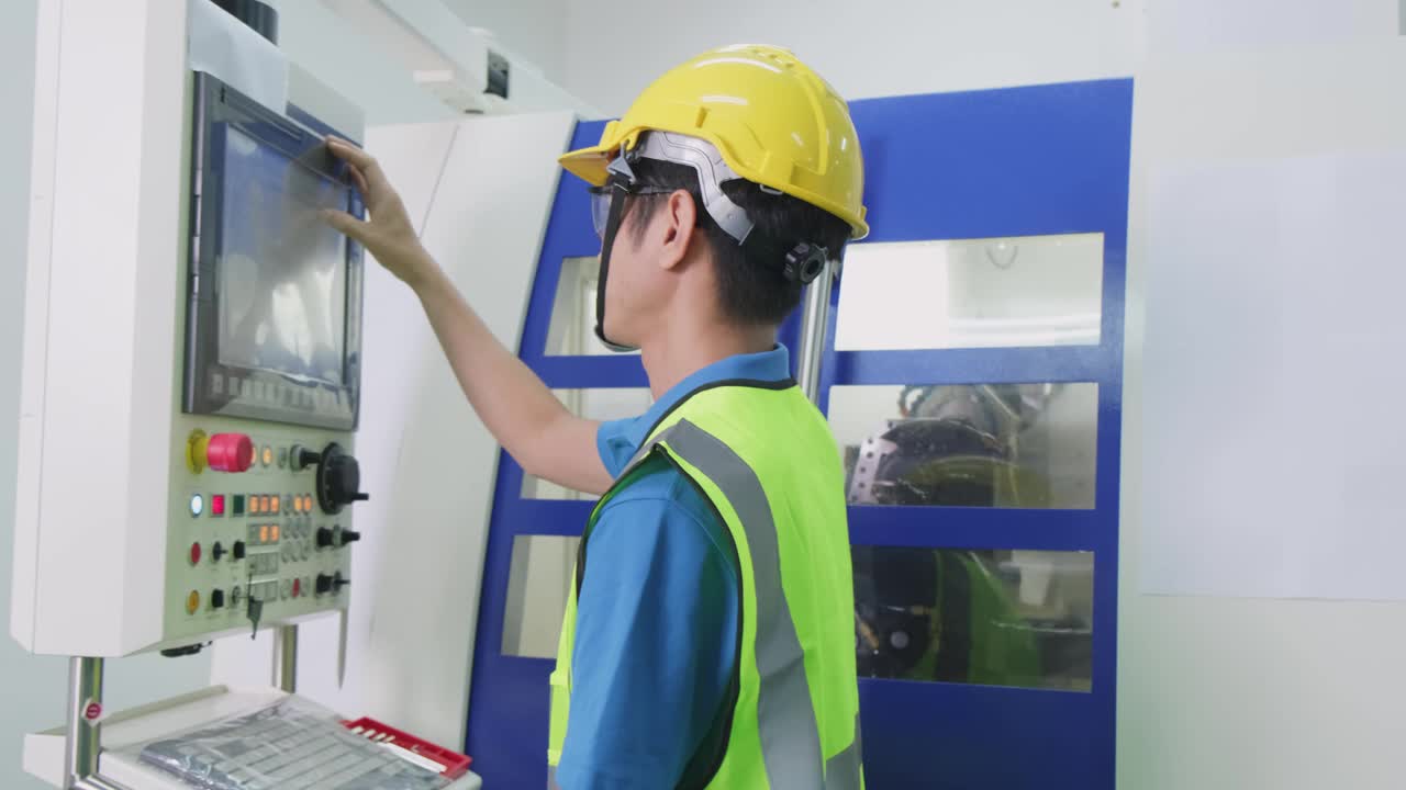 工厂生产线上戴防护安全帽和眼镜的男工人。在工厂里操作高科技机器的男人，面带自信和微笑。视频购买
