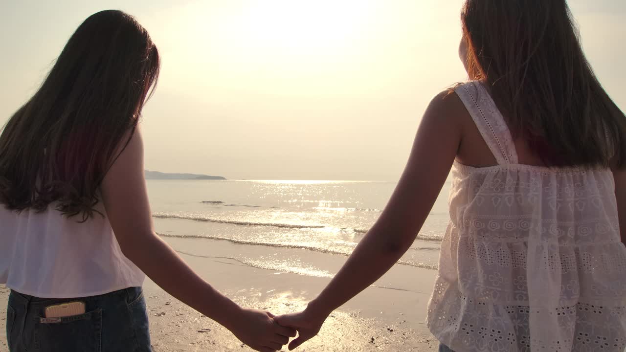 两个年轻的女性朋友有乐趣在日落海滩视频素材