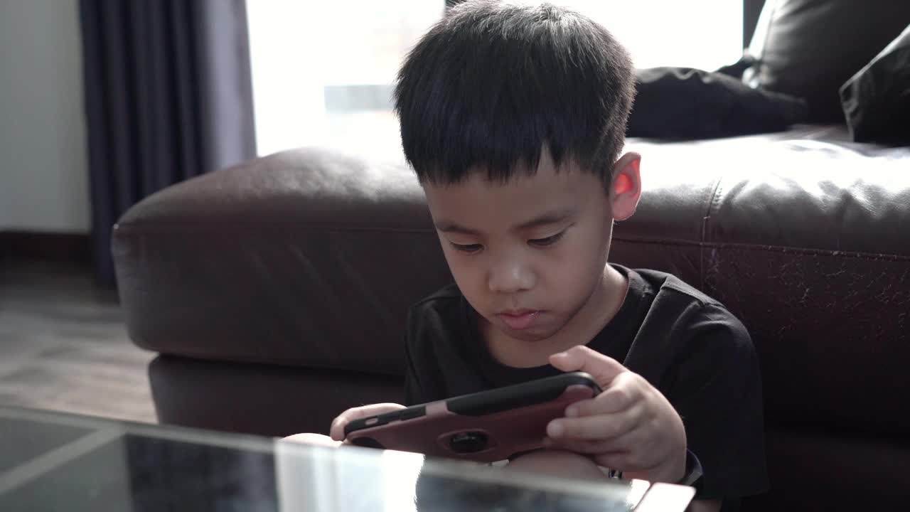 亚洲男孩用智能手机玩游戏。视频下载