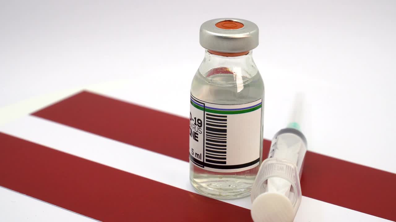 COVID-19疫苗和带有拉脱维亚国旗的注射器视频下载