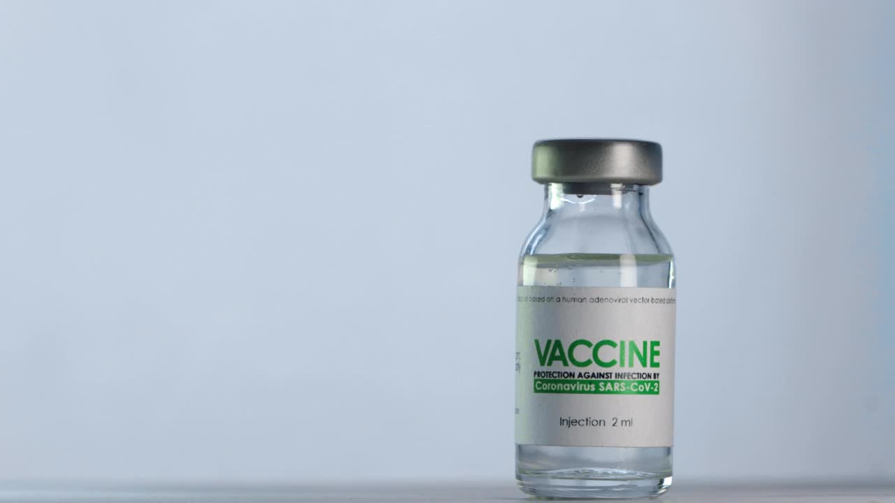 医生在注射前将治疗COVID-19的疫苗瓶装满注射器。大流行疫苗接种的概念。针穿过瓶盖，进入小瓶内。医用手套。宏广角镜头视频素材